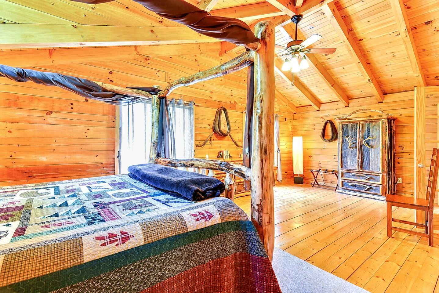 Une chambre confortable dans un chalet, avec un lit, un ventilateur de plafond et un intérieur rustique en bois.