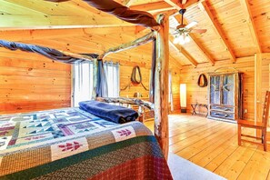 Ein gemütliches Cabin-Zimmer mit Bett, Deckenventilator und rustikalem Holzinnenraum.
