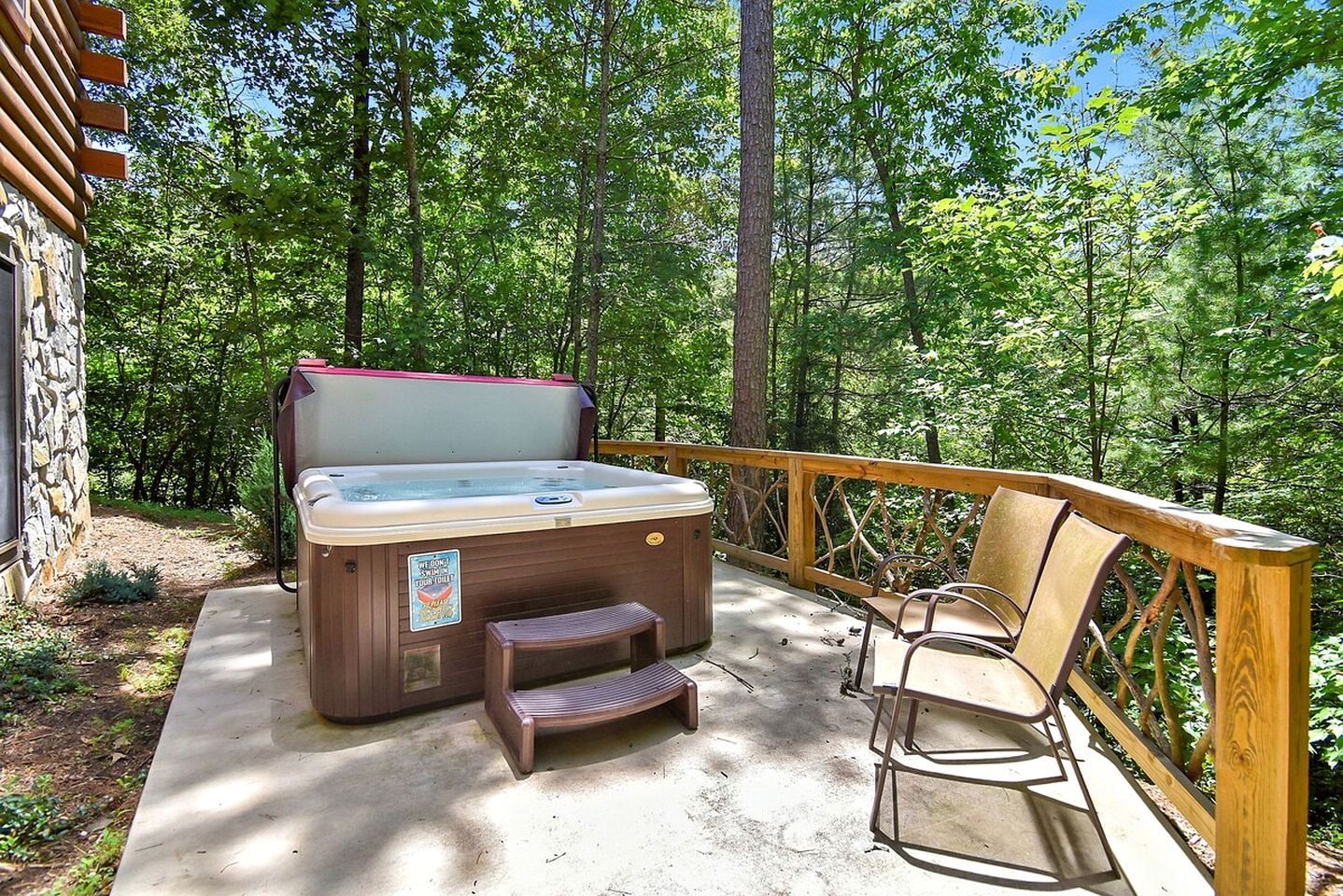 A hot tub on a wooden deck with a wooden chair and a wooden stool.