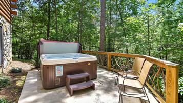 A hot tub on a wooden deck with a wooden chair and a wooden stool.