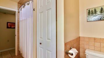 A bathroom with a toilet, a shower curtain, and a toilet paper holder.
