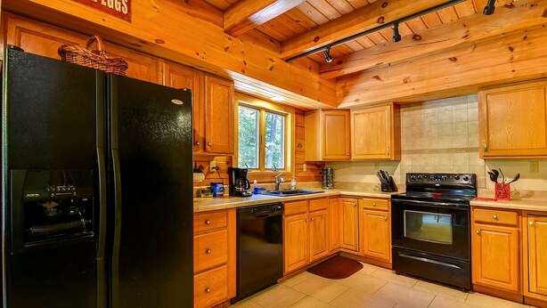 Una cocina con armarios de madera, un refrigerador negro, una estufa y un lavavajillas.