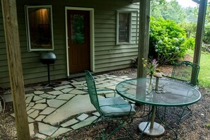 A covered patio with a stone floor, a green metal table and chairs, and a door with a window. - Cozy Ground Floor Suite in a Beautiful Farmhouse for a Unique Getaway in Afton, Virginia (Afton)