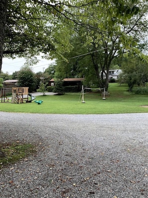 A residential area with a grassy lawn, a swing set, and a small play structure. - Cozy Creekside Cabin Rental in Bryson City, North Carolina (Bryson City)