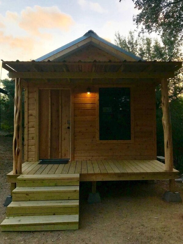 Une cabane en bois avec une véranda, une porte et une fenêtre.