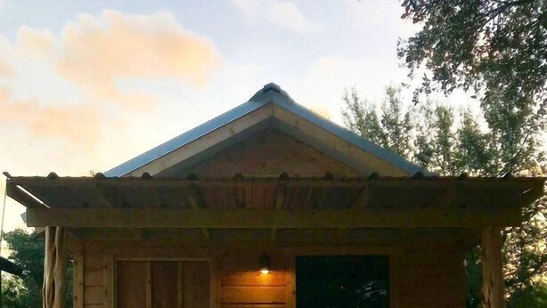 Eine Holzhütte mit Veranda, Tür und Fenster.