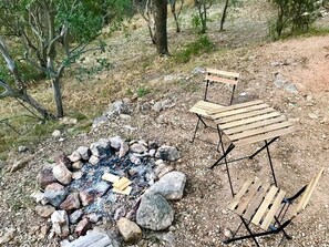 Un terrain de camping avec un foyer entouré de rochers et deux bancs en bois.