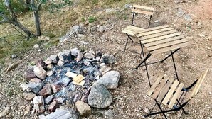 Un terrain de camping avec un foyer entouré de rochers et deux bancs en bois.