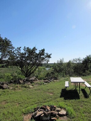 Un área de picnic con una mesa y bancos, rodeada de rocas y árboles.