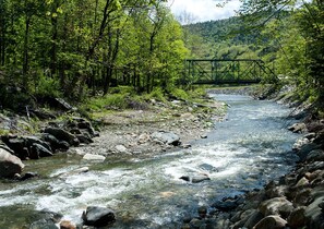 A river with rocks and a bridge in a forested area. - Custom Cabin Surrounded by River in Newfane, Vermont (South Newfane)