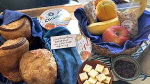 Aamiaistarjotin, jossa on leipää, hedelmiä, jogurttia ja pieni viesti.