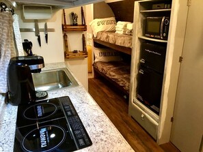 A compact kitchenette with a stovetop, sink, and microwave.