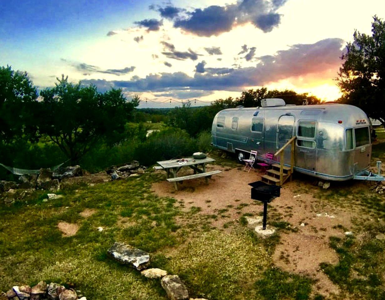 A trailer with a picnic table and a grill set up in a grassy area.