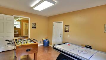 A room with a foosball table and an air hockey table, with a door leading to another room.