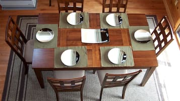 Un tavolo da pranzo in legno con sei sedie, ognuna con un sottopiatti riflettente.