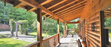 A wooden deck with a swing chair and a bench, surrounded by a wooden cabin structure.