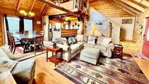 Interior acogedor de una cabaña de madera con comedor, asientos y chimenea.