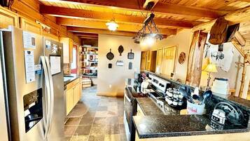 A kitchen with a refrigerator, stove, and granite countertop.