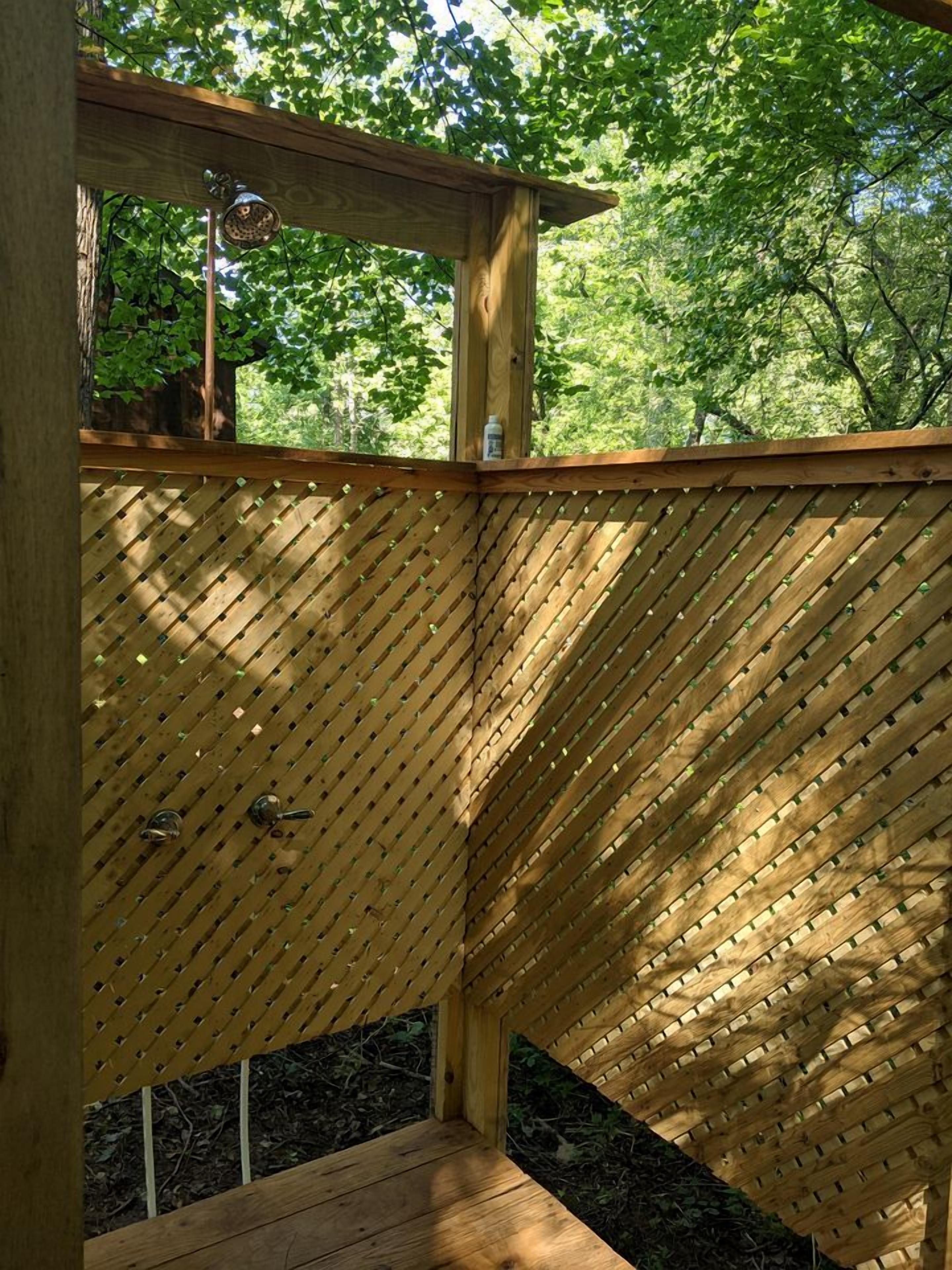 A wooden deck with a slatted design, surrounded by trees.