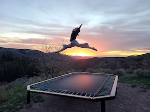 Un trampolín en un entorno natural, con un atardecer de fondo.