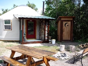 A yurt with a porch, a wooden bench, and a small wooden structure with a crescent moon and star. - Secluded Cozy Yurt for Luxury Camping near Pocatello, Idaho (Pocatello)