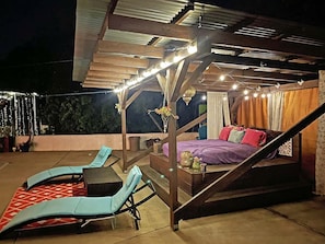 An outdoor patio with lounge chairs, a bed, and string lights. - Lovely Glamping Tent for Three with a Shared Pool near Lakeside, California (El Cajon)