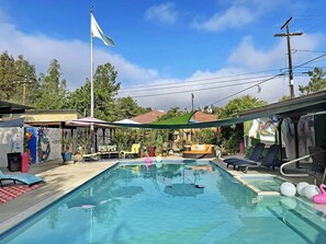 A swimming pool with lounge chairs, a flag, and a mural.