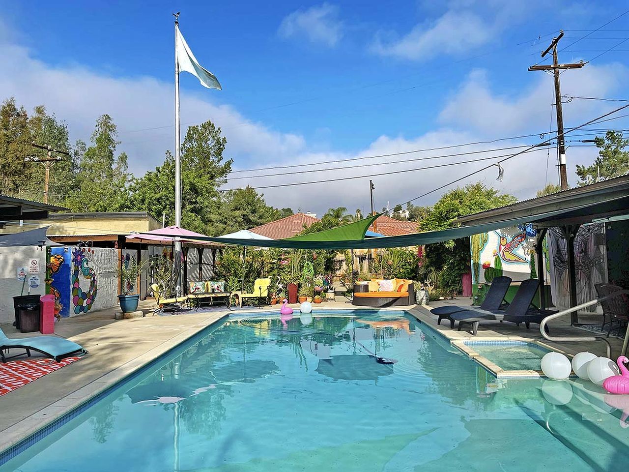 A swimming pool with lounge chairs, a flag, and a mural.