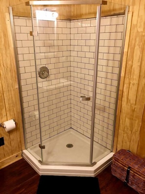 A corner shower with glass doors and white tiled walls.