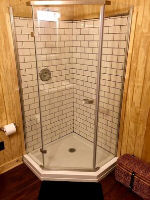 A corner shower with glass doors and white tiled walls.
