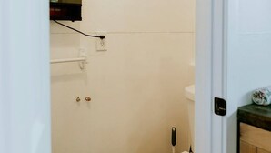A small, clean bathroom with a toilet, a hand dryer, and a towel rack.