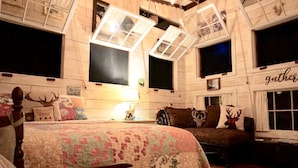 Una habitación rústica con cama, sofá y una ventana con la palabra 'gather'.