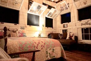 Une chambre rustique avec un lit, un canapé et une fenêtre sur laquelle est inscrit le mot «rassemblement».