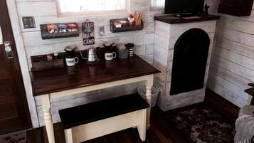 Una cocina compacta con una mesa de madera, una cafetera y un televisor sobre un mueble.