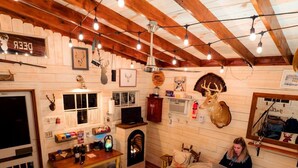 A cozy room with wooden beams, a fireplace, a bed with a colorful quilt, and various wall decorations including animal heads.