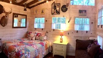 Ein rustikales Cabin-Zimmer mit einem Bett, einem Nachttisch, einer Lampe und Hirschgeweihen an der Wand.