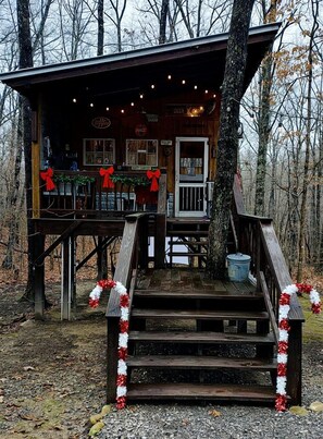 Une cabane en bois avec une terrasse, une pancarte indiquant « Camp des cerfs » et une couronne de Noël.
