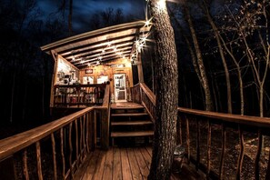 Une terrasse en bois avec un escalier menant à un bâtiment, le tout entouré d’arbres.