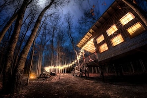 Eine rustikale Holzhütte mit mehreren Fenstern, einer Veranda und einer Lichterkette.