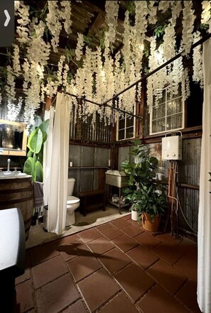 Une salle de bain rustique avec un lavabo en forme de tonneau en bois, des toilettes et un rideau de douche.