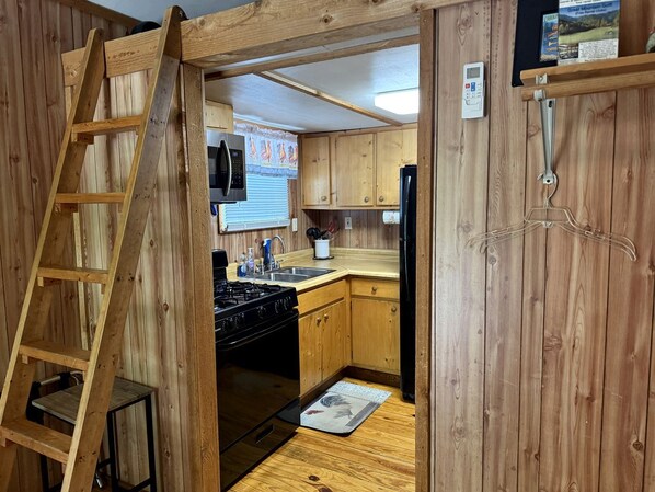 Cocina compacta con armarios de madera, estufa y microondas.