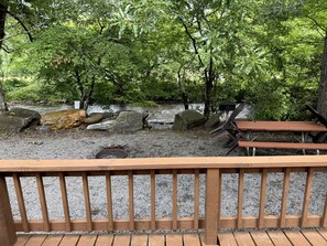 A wooden deck with benches overlooking a natural area with rocks and trees.