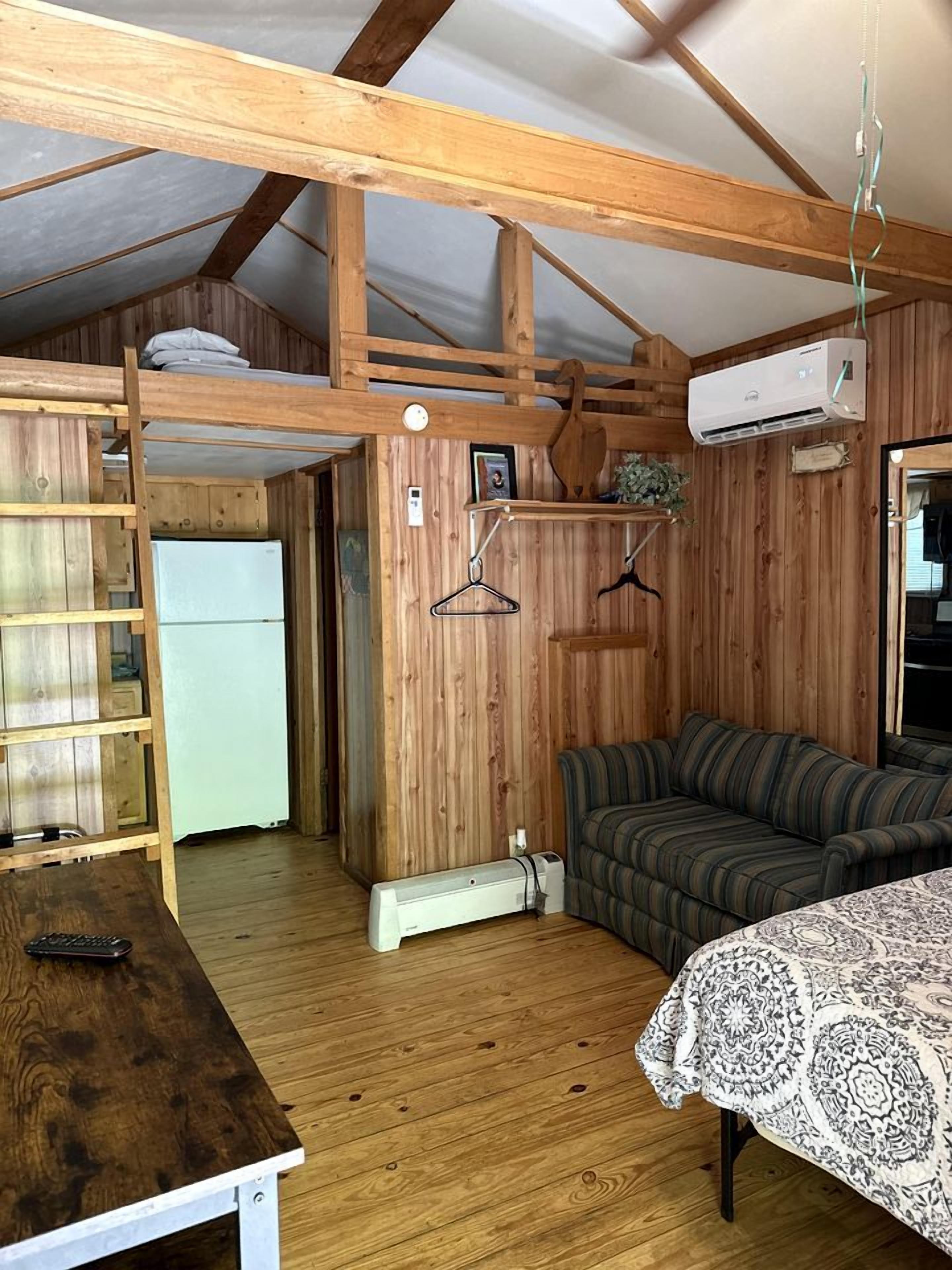 Une petite pièce comprenant un lit superposé, un canapé, une petite table et un radiateur.