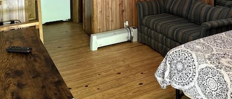 Une petite pièce comprenant un lit superposé, un canapé, une petite table et un radiateur.