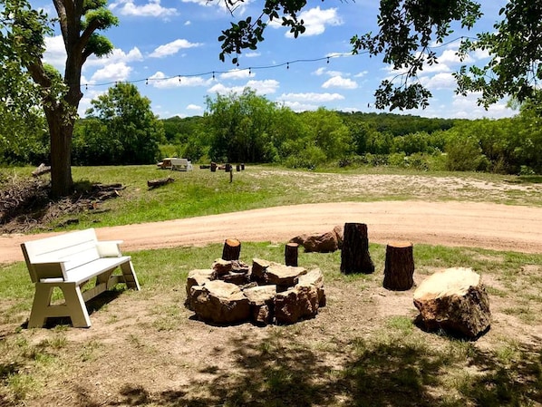 A park with a white bench, a dirt path, and several tree stumps.
