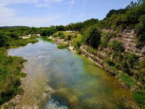 A river flowing through a natural landscape with greenery and rocky terrain.