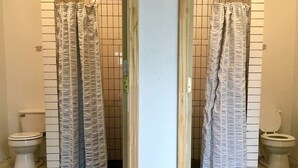 Une salle de bain avec un rideau de douche à rayures, des toilettes et un mur carrelé.
