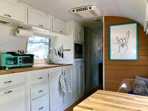 A compact kitchen with white cabinets, a microwave, and a sink.