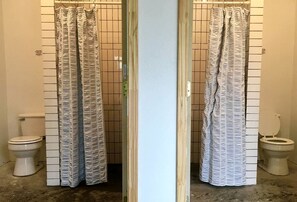 A bathroom with a striped shower curtain, a toilet, and a tiled wall.