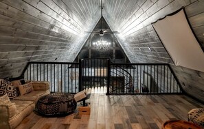 An attic bedroom with a sloped ceiling, a chandelier, a staircase, and a view of the sky.